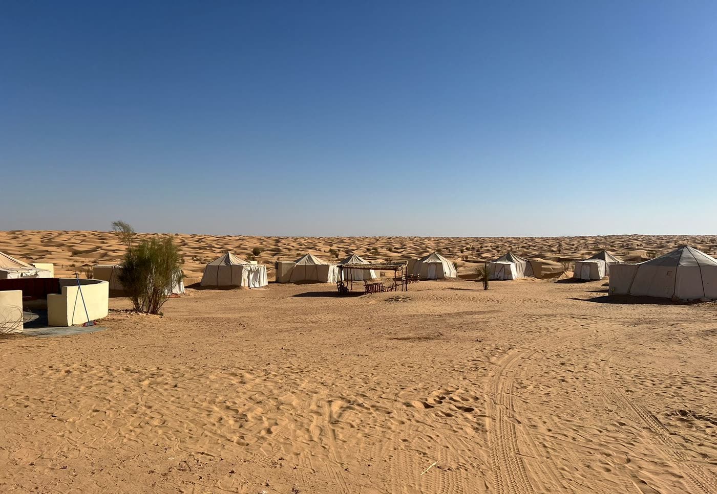 Tented camp spread across the sand under a clear sky