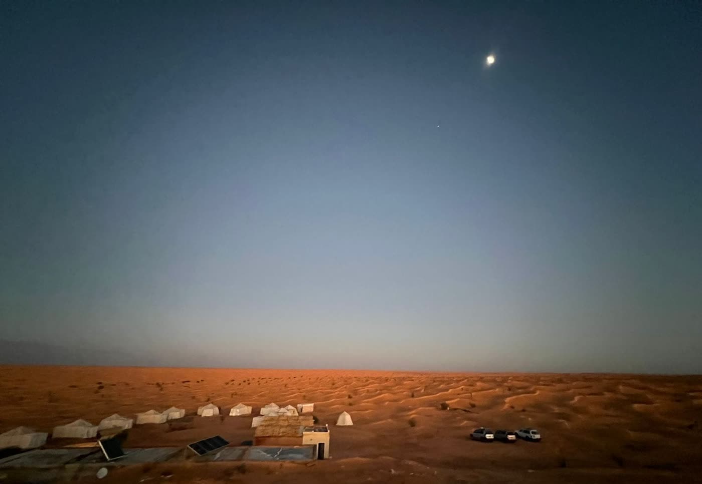 The camp at dusk, the moon already up over the dunes