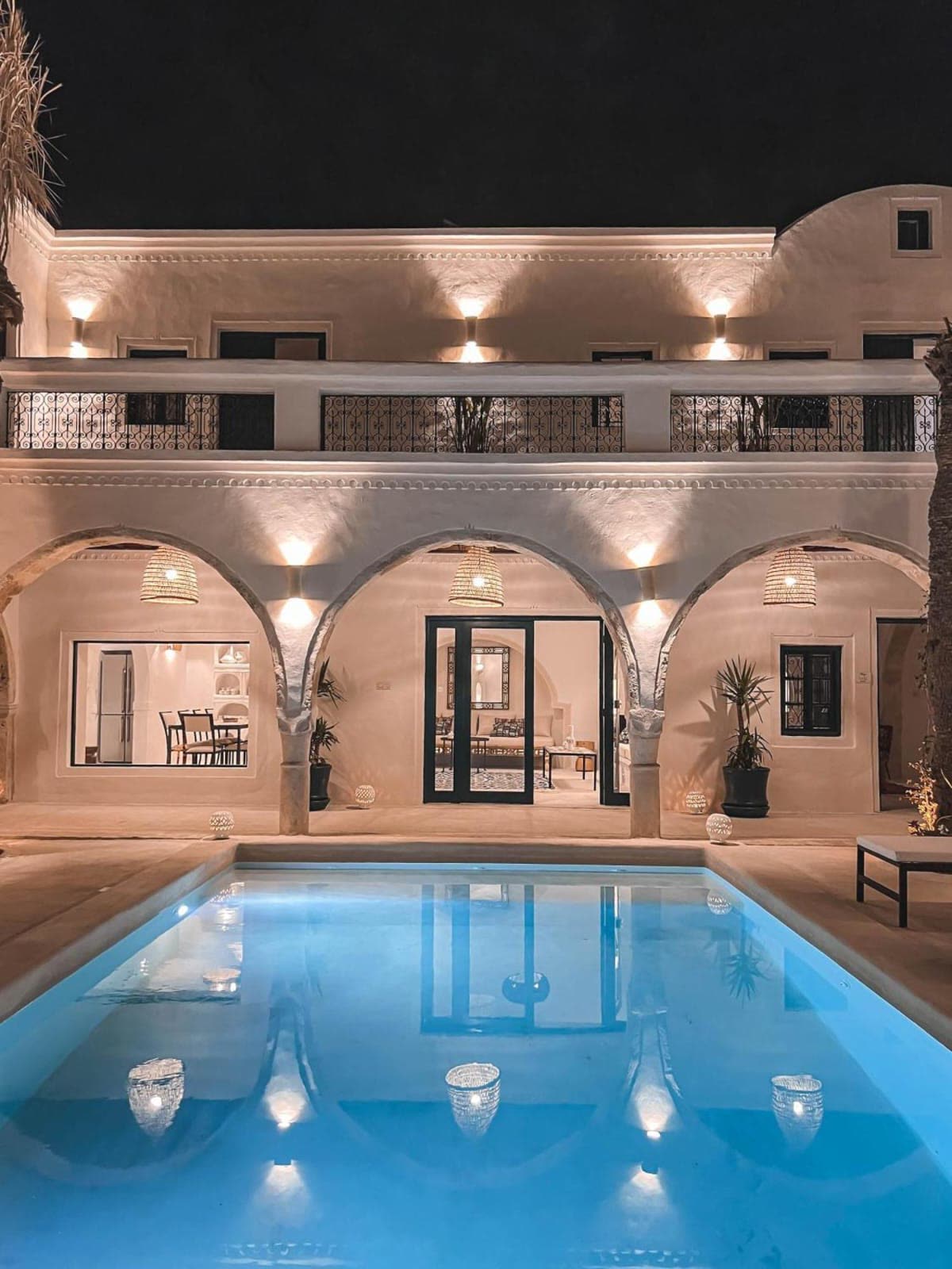 Courtyard pool lit at night beneath vaulted arches