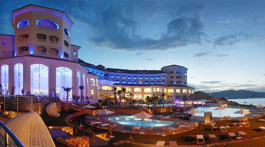 A coastal resort lit up at dusk above its pools